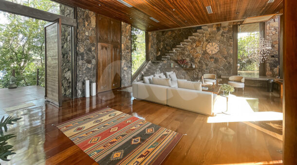 Imagem de ampla sala de estar em piso de madeira e paredes de pedra da Ilha à venda em Angra dos Reis.