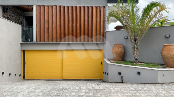Imagem de garagem com portao amarelo da casa triplex à venda no condomínio Art Life, no Recreio dos Bandeirantes.