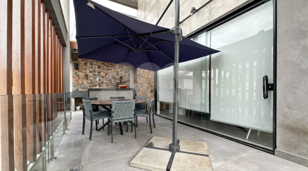Imagem dearea gourmet com ombrelone e ripas de madeira em decoração externa da casa triplex à venda no condomínio Art Life, no Recreio dos Bandeirantes.